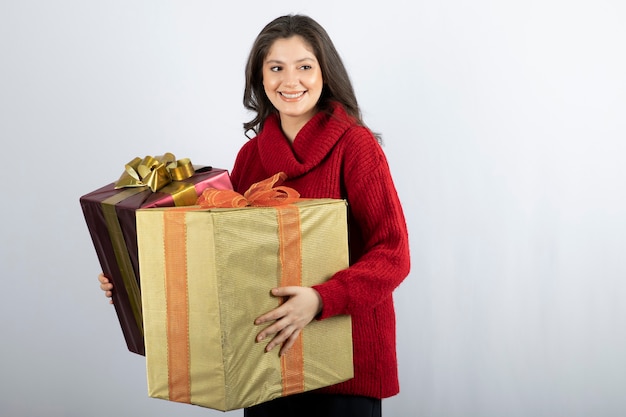 Bella donna in maglione rosso che tiene i regali di Natale.