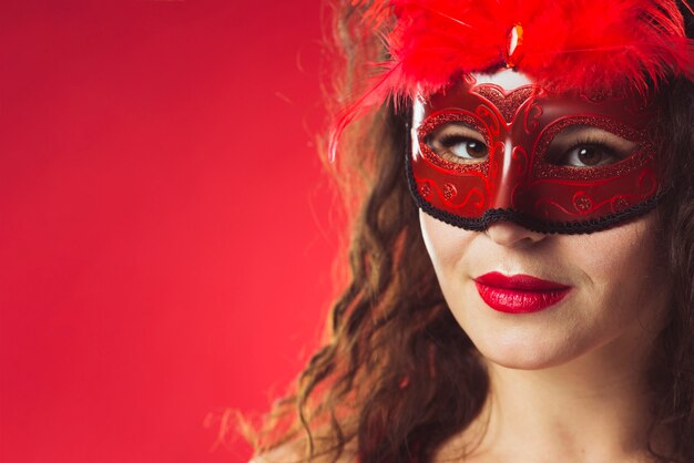 Bella donna in maschera rossa con piume