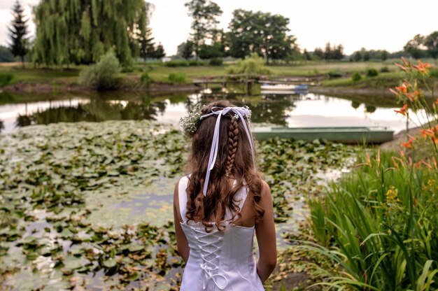 Bella donna in piedi davanti a un laghetto nel bellissimo giardino