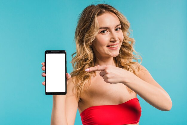 Bella donna in rosso in alto in possesso e che punta al telefono cellulare