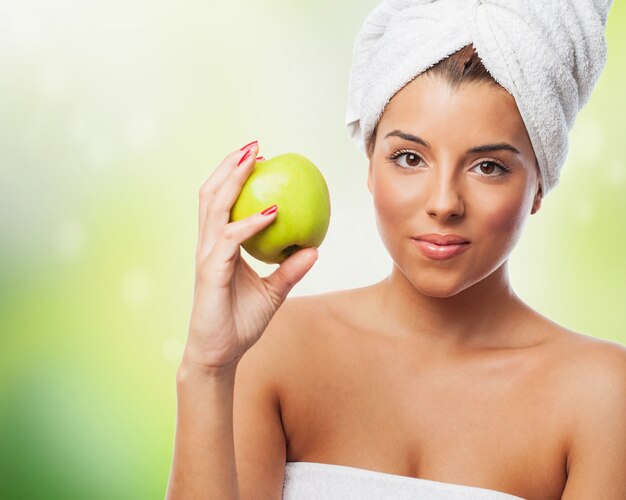 Bella donna in un asciugamano in possesso di mela verde