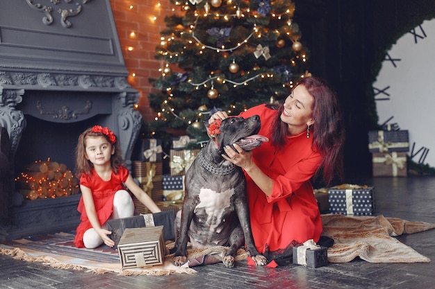 Bella donna in un vestito rosso. Famiglia a casa. Madre con figlia. Persone con un cane.