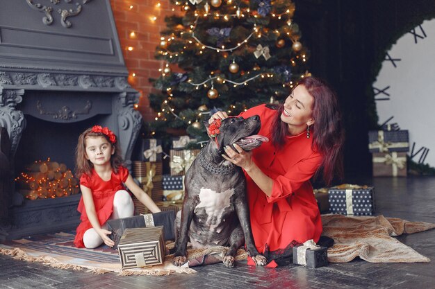 Bella donna in un vestito rosso. Famiglia a casa. Madre con figlia. Persone con un cane.