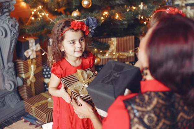 Bella donna in un vestito rosso. Famiglia a casa. Madre con figlia.