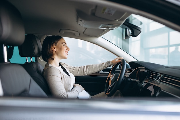 Bella donna incinta che guida in auto