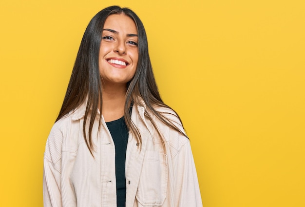 Bella donna ispanica che indossa abiti casual dall'aspetto positivo e felice in piedi e sorridente con un sorriso fiducioso che mostra i denti