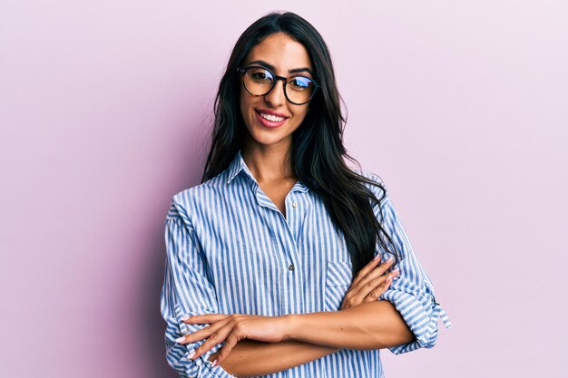 Bella donna ispanica che indossa abiti casual e occhiali faccia felice sorridente con le braccia incrociate guardando la telecamera. persona positiva.