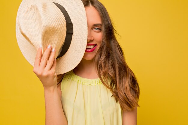 Bella donna ispirata con lunghi capelli ondulati che copre il viso con il cappello