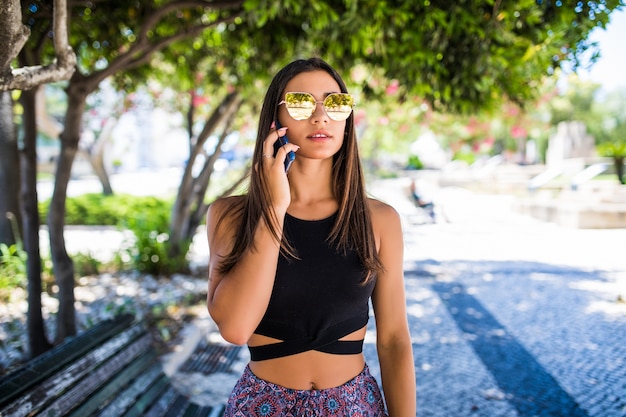 Bella donna latina parlando al telefono e sorridente in un parco