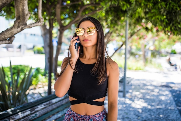 Bella donna latina parlando al telefono e sorridente in un parco