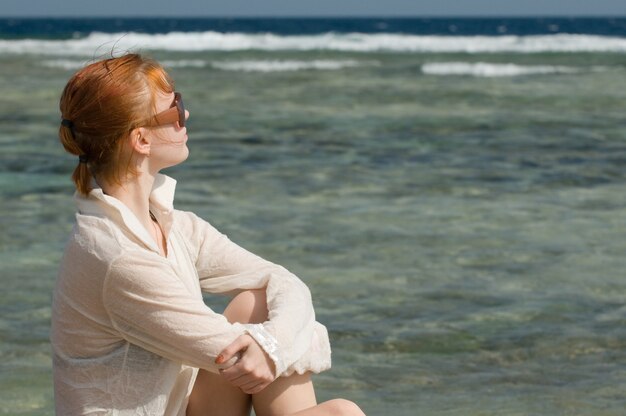 Bella donna rossa che si distende dall&#39;oceano