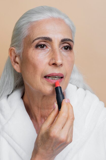 Bella donna senior che applica rossetto