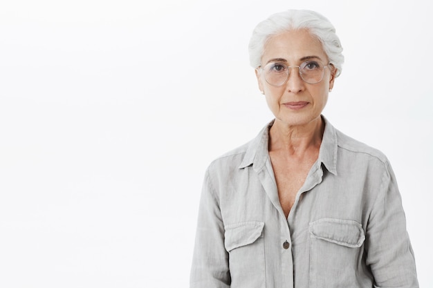 Bella donna senior con gli occhiali sorridente, sfondo bianco