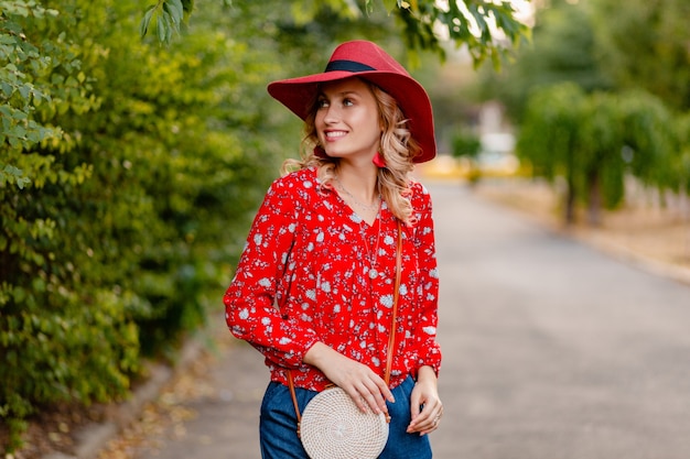 Bella donna sorridente bionda elegante attraente in cappello rosso di paglia e vestito di moda estiva camicetta