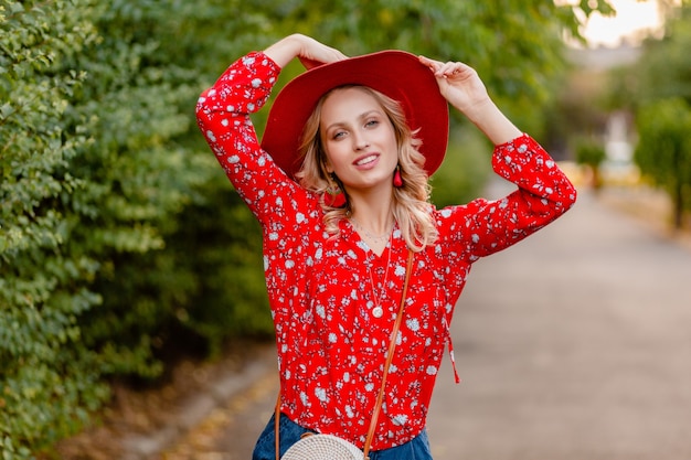 Bella donna sorridente bionda elegante attraente in cappello rosso di paglia e vestito di moda estiva camicetta