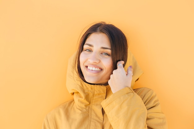 bella donna sorridente che indossa giacca felpa con cappuccio giallo guardando la fotocamera