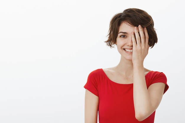 Bella donna sorridente che sembra felice, coprire metà del viso con il palmo