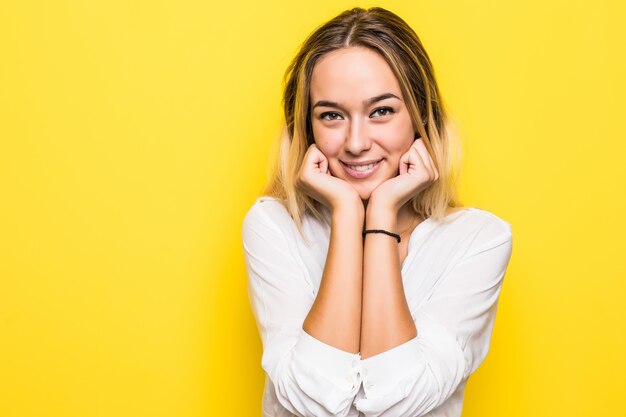 Bella donna sorridente con pelle pulita e denti bianchi in posa sulla parete gialla