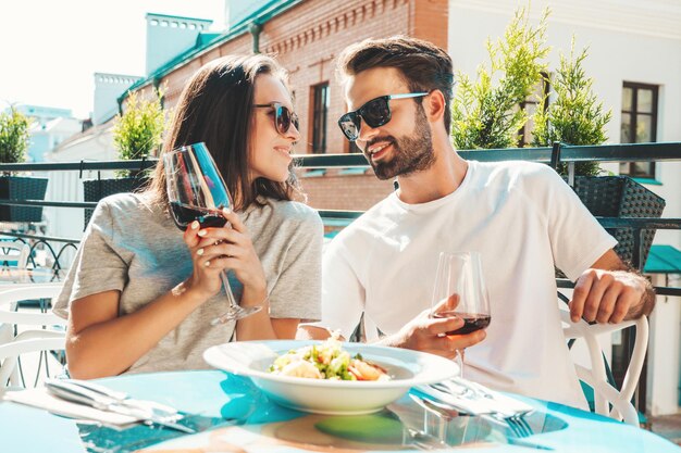 Bella donna sorridente e il suo bel ragazzo Famiglia allegra felice Coppia tifo con bicchieri di vino rosso al loro appuntamento nel ristorante Bevono alcolici al caffè veranda in strada