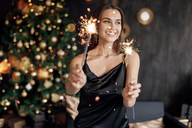 bella donna sorridente in abito con champagne e fuochi d'artificio