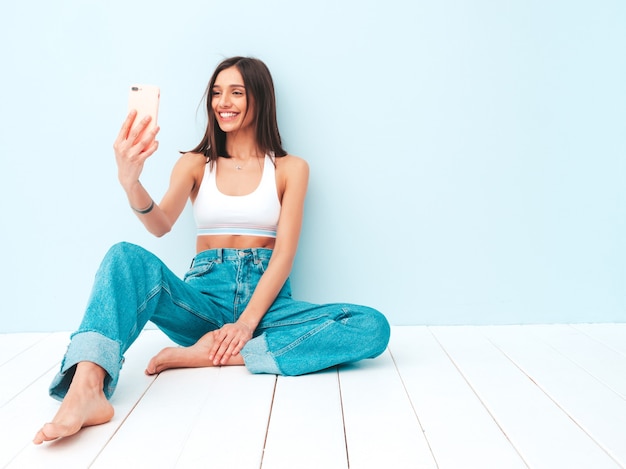 Bella donna sorridente vestita di maglia bianca e jeans. modella allegra spensierata che si gode la mattinata