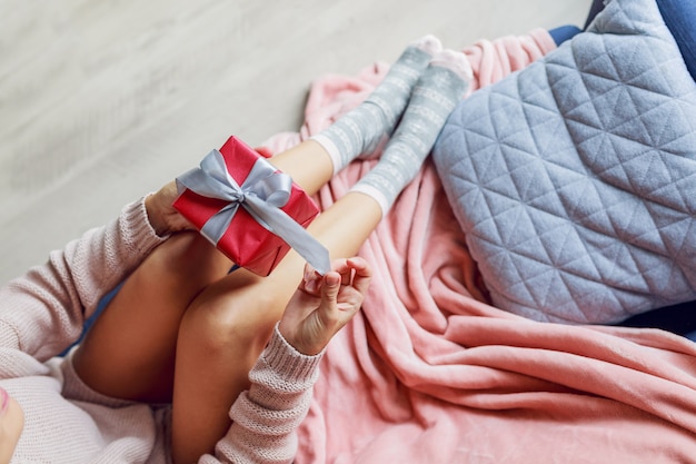 Bella donna sul divano in possesso di un regalo