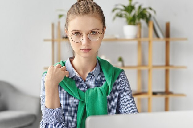 Bella donna vestita formalmente in ufficio con il computer portatile