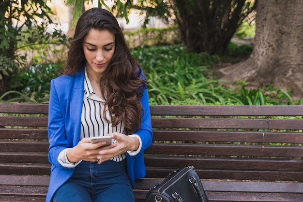 Bella esecutivo utilizzando il suo cellulare nel parco