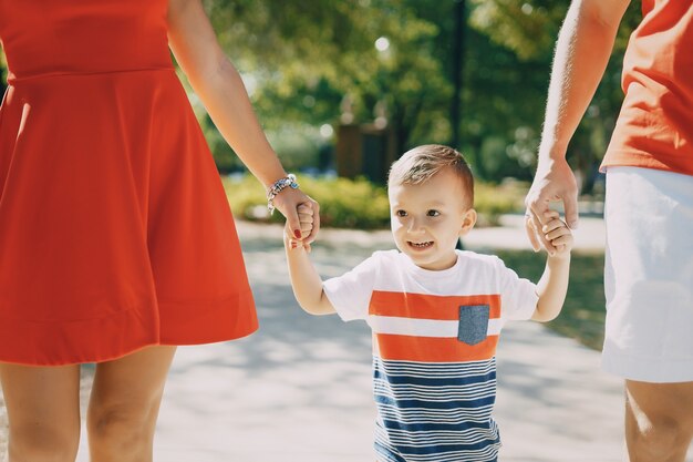 Bella famiglia in rosso camminando lungo la strada e il parco