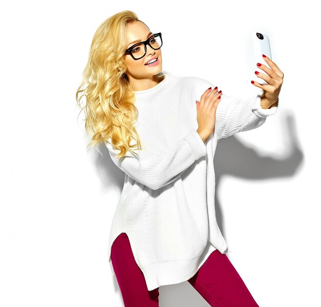 bella felice dolce carina donna bionda sorridente in abiti casual caldo maglione bianco hipster, in bicchieri prendendo selfie