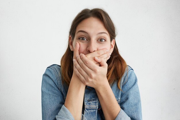 Bella femmina castana che scoppia a ridere che copre la bocca