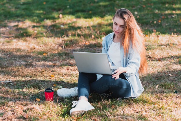 Bella femmina che lavora al computer portatile nel parco