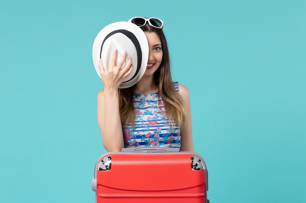 Bella femmina di vista frontale che prepara per la vacanza con la borsa rossa sullo spazio blu