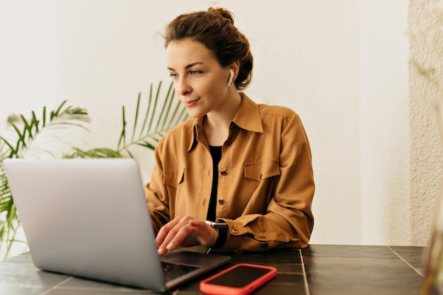 Bella gioiosa donna bruna in cuffia sta lavorando su un computer portatile sul tavolo surround lavoro roba Allegro stato d'animo prendendo una pausa lavorando studio relax vera emozione