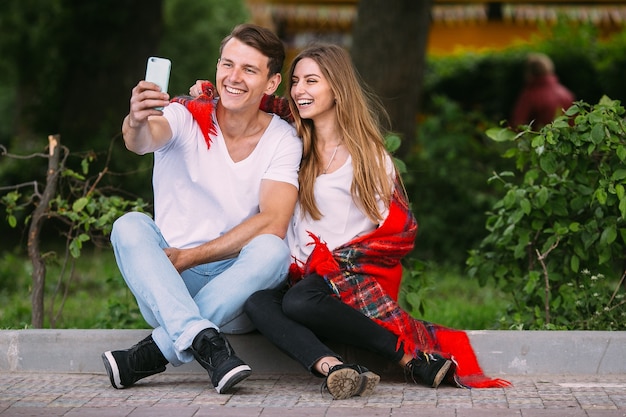Bella giovane coppia che si rilassa nel parco e fa selfie