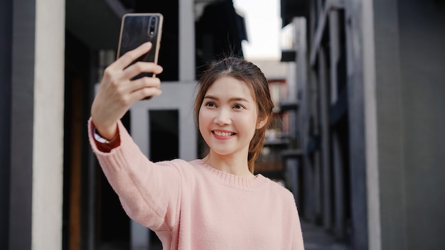 Bella giovane donna asiatica allegra di blogger dello zaino in spalla che per mezzo dello smartphone che prende selfie mentre viaggiando a Chinatown a Pechino, la Cina.