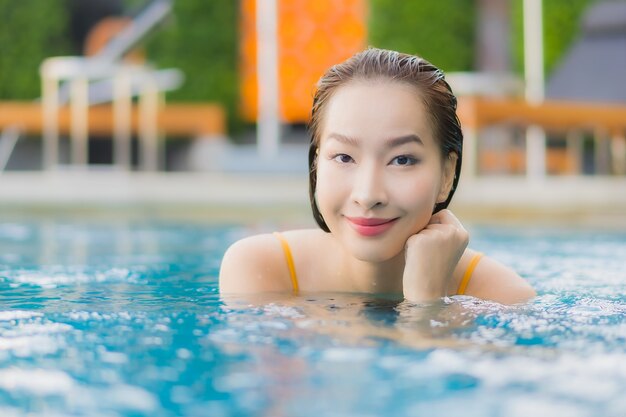 Bella giovane donna asiatica del ritratto che si rilassa all'aperto nella piscina in viaggio di festa