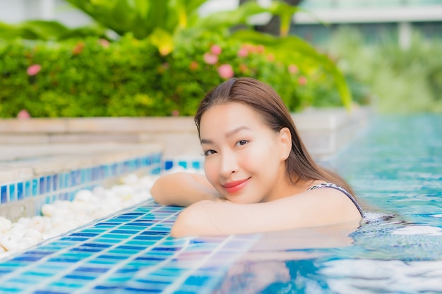 Bella giovane donna asiatica del ritratto che si rilassa all'aperto nella piscina in viaggio di festa