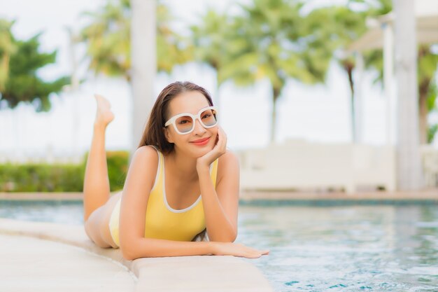 Bella giovane donna asiatica del ritratto che si rilassa all'aperto nella piscina in viaggio di festa