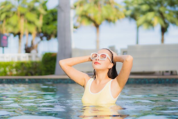 Bella giovane donna asiatica del ritratto che si rilassa all'aperto nella piscina in viaggio di festa