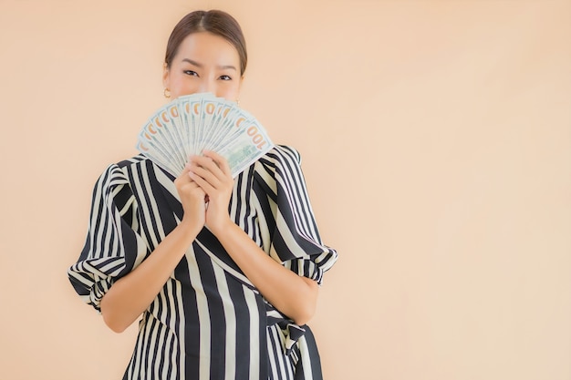 Bella giovane donna asiatica del ritratto con contanti e soldi