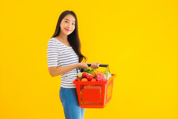 Bella giovane donna asiatica del ritratto con il carretto del canestro della drogheria dal supermercato nel centro commerciale
