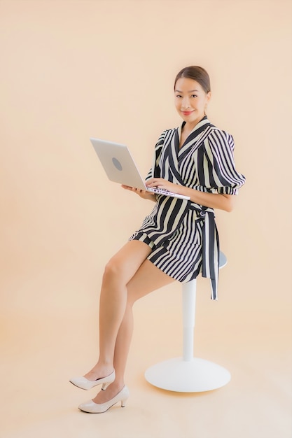 Bella giovane donna asiatica del ritratto con il computer portatile o il computer