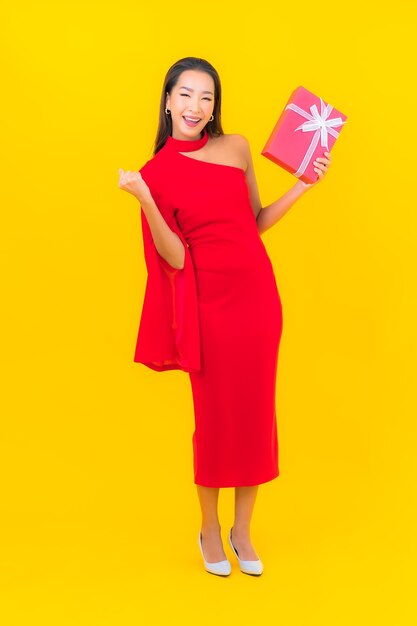 Bella giovane donna asiatica del ritratto con il contenitore di regalo rosso