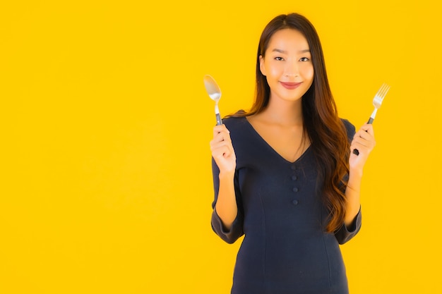 Bella giovane donna asiatica del ritratto con il cucchiaio e la forchetta