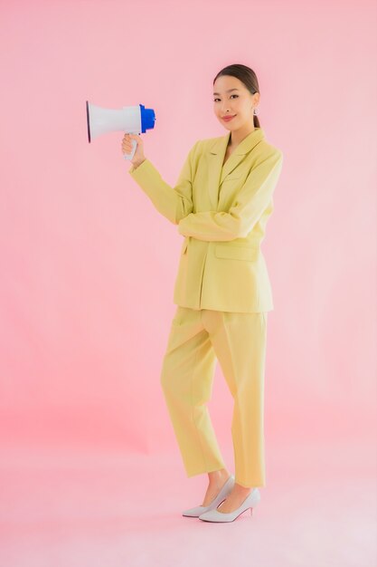 Bella giovane donna asiatica del ritratto con il megafono sul colore