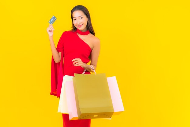 Bella giovane donna asiatica del ritratto con il sacchetto della spesa e la carta di credito