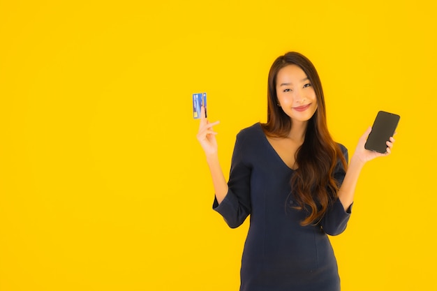Bella giovane donna asiatica del ritratto con il telefono e la carta di credito