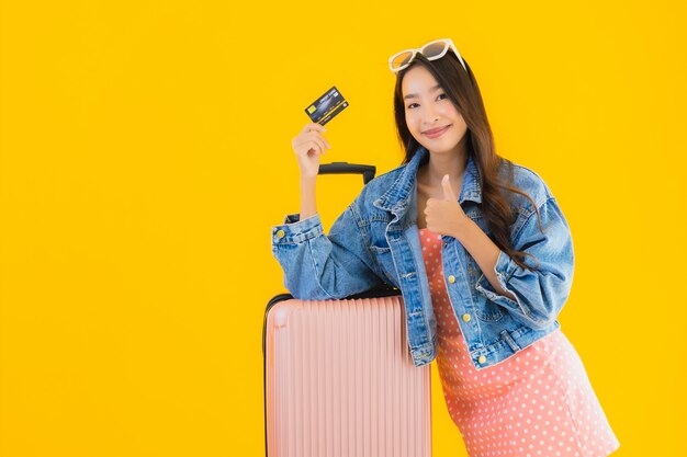Bella giovane donna asiatica del ritratto con la borsa di viaggio dei bagagli con il biglietto del passaporto e di imbarco