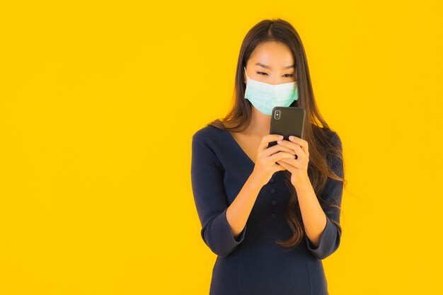 Bella giovane donna asiatica del ritratto con la maschera e il telefono